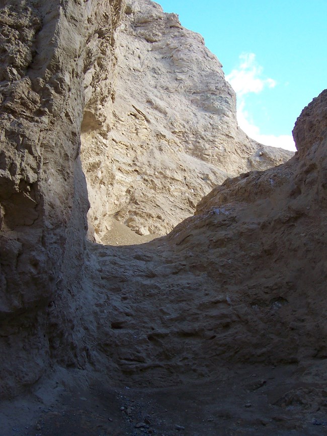 A dry waterfall blocks passage inside a narrow canyon.