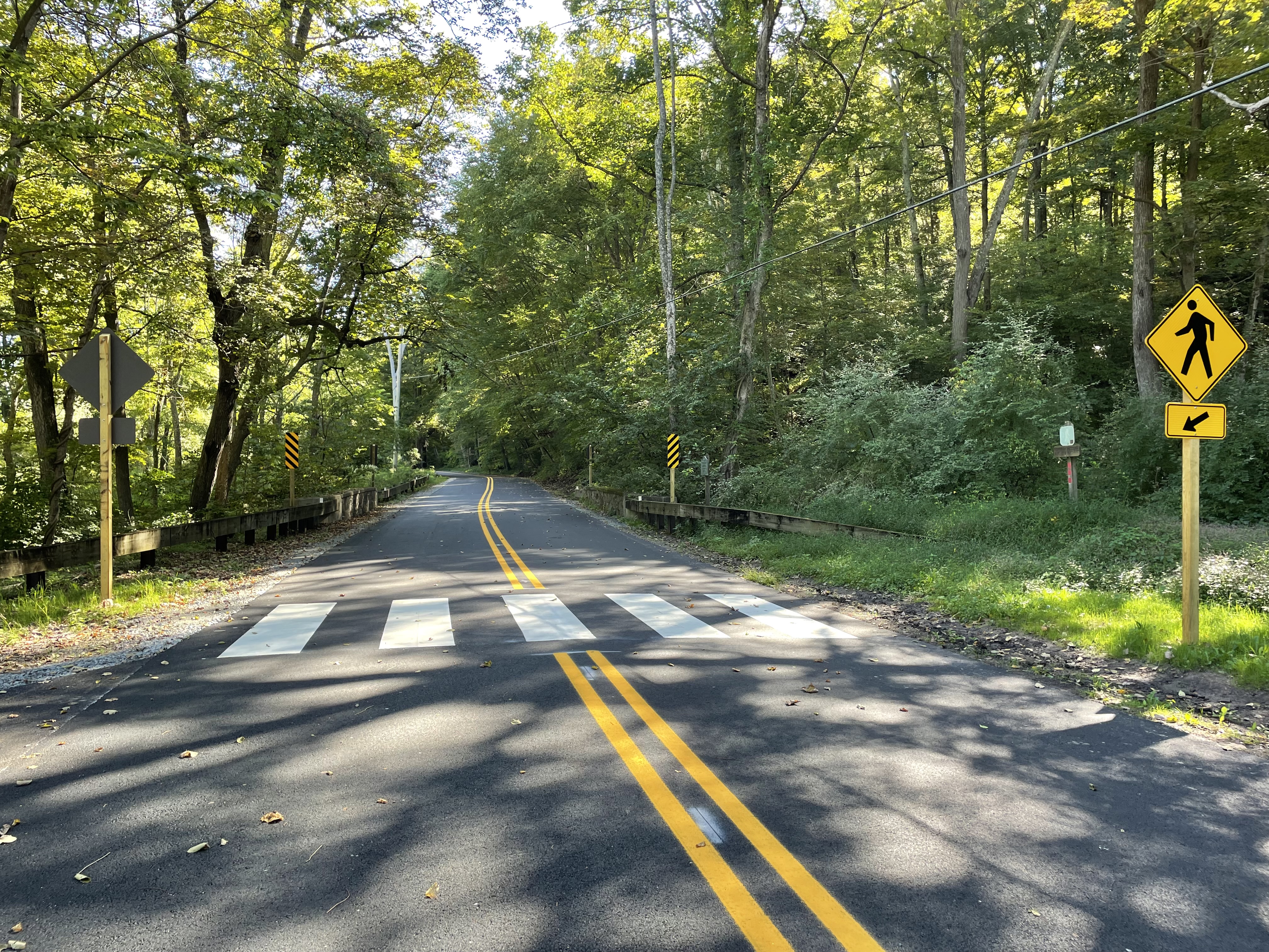 A freshly paved road with a painted crosswalk.