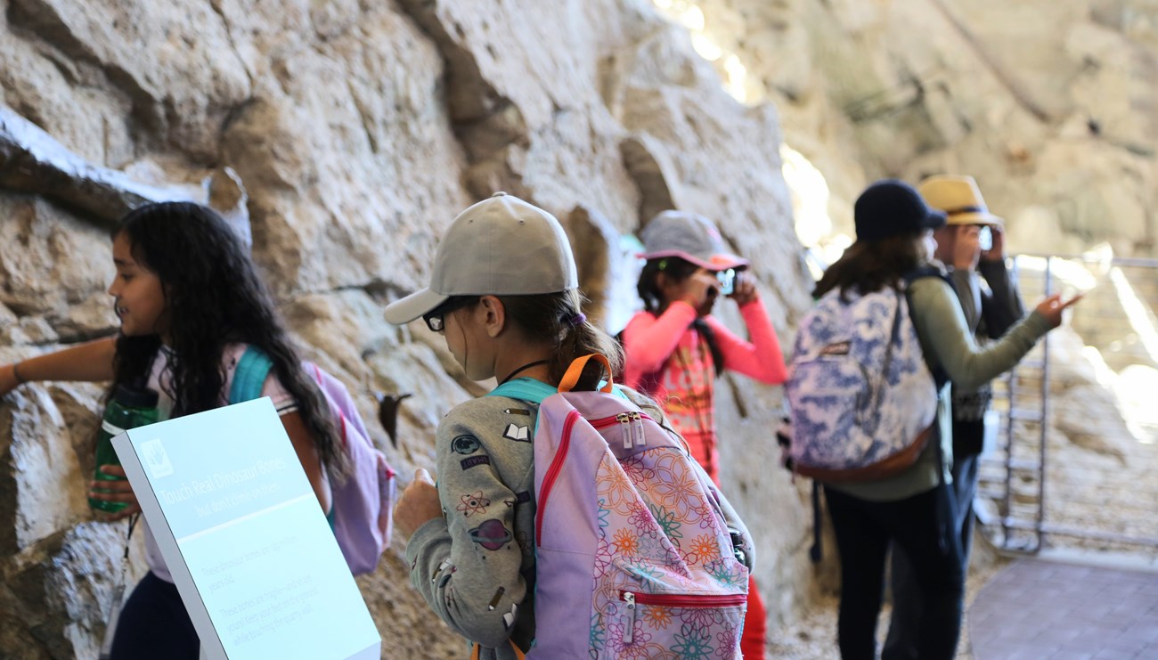 Children with backpacks read signs and examine the fossils at the Quarry Exhibit Hall.