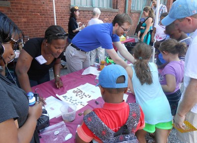 Families at a table learning to do a science experiment.