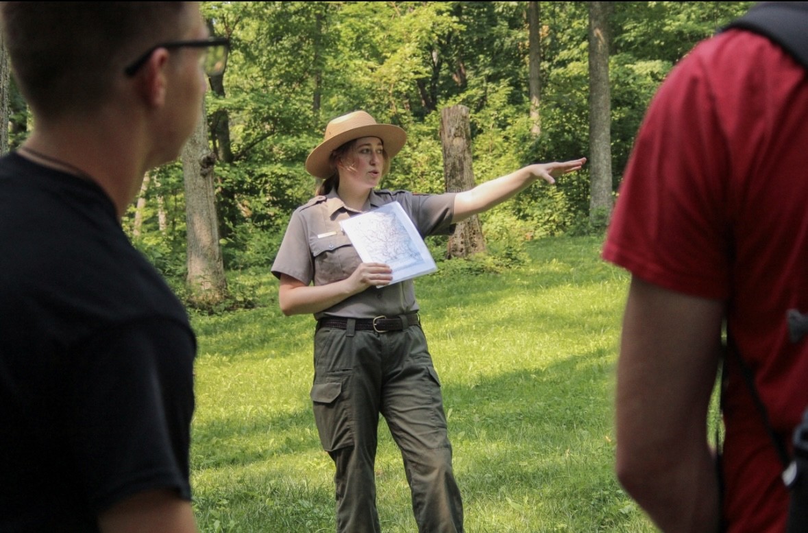 A park ranger pointing at something not seen.