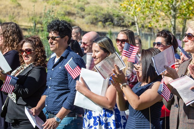 A group of new citizens raise their hands and wave American flags