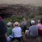 Ranger leads bat program to a group of visitors in front of a cave