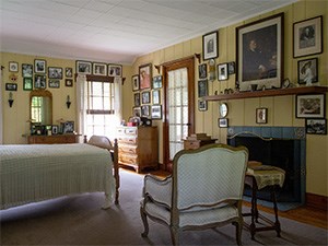 A bedroom with many photographs hanging on the walls.