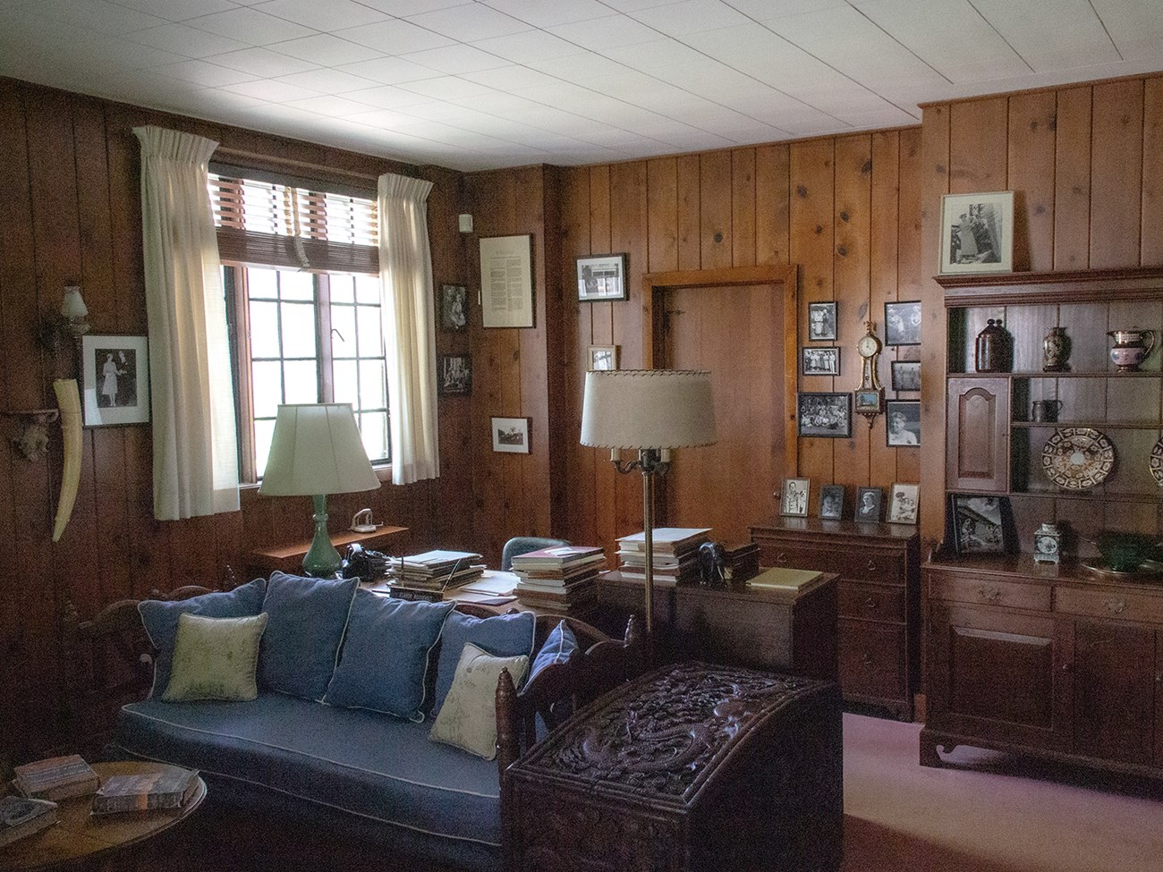 A paneled room with upholstered and many photos on the walls.