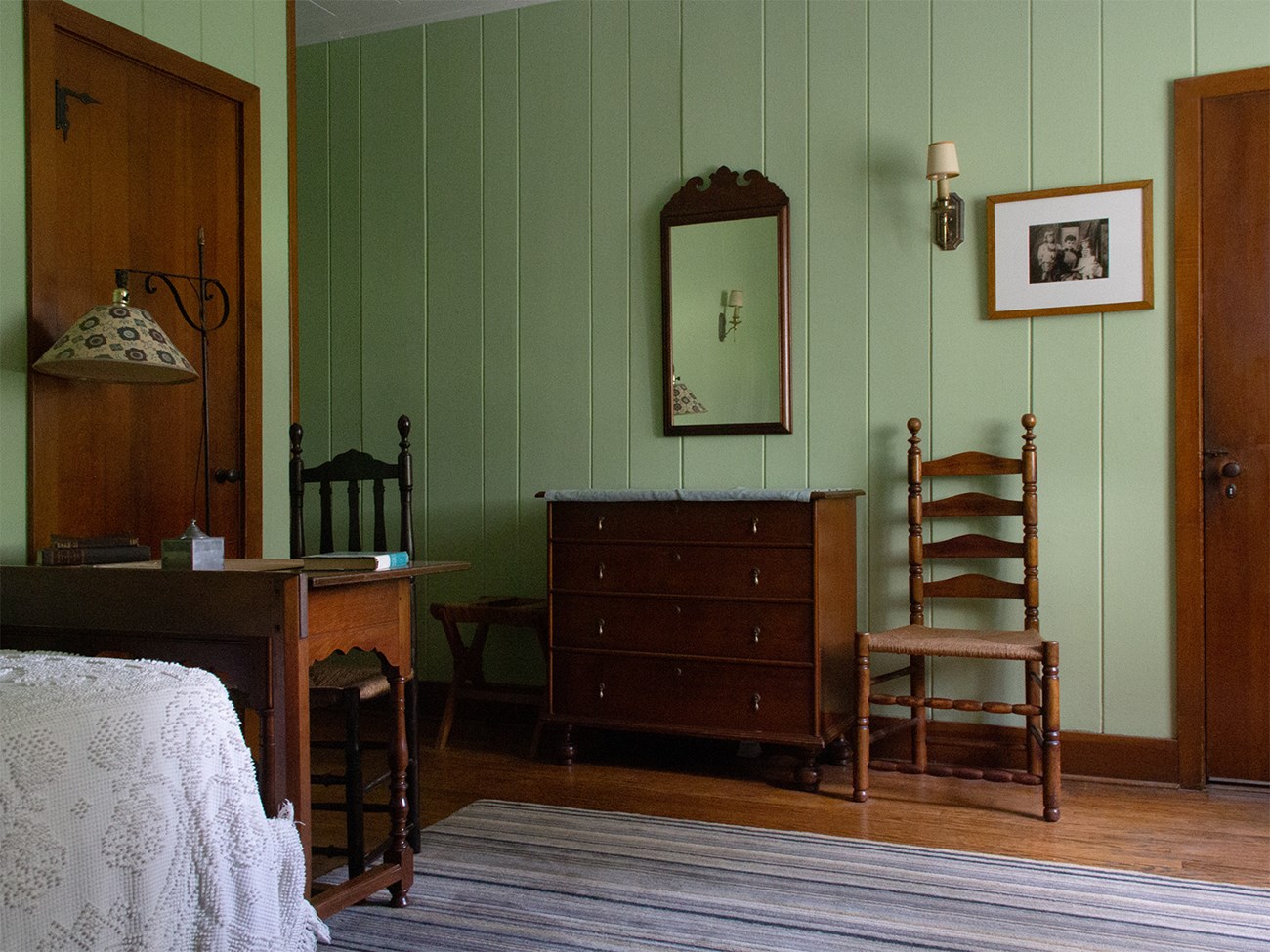 A room with beds, desk, and a chest of drawers.