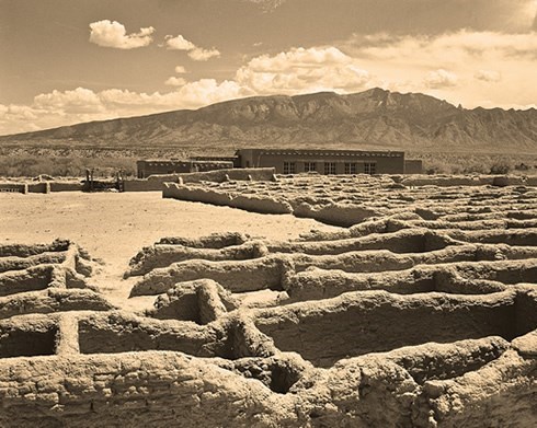 historical photo of kuaua ruins, with remains of walls and mountains in the back