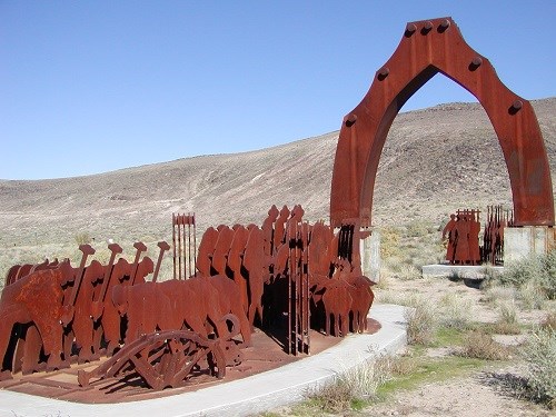 monument of a door, people and animals made out of metal