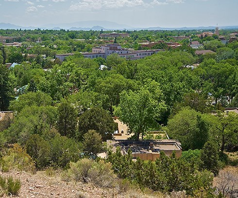 view of Santa Fe's church, houses, trees and mountains in the back