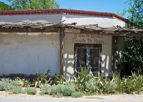 old white house with a sign in spanish that reads "store of clothes"