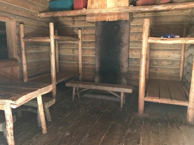 Un cuarto con dos camarotes, un escritorio y lugar para un fuego conectado a un cuarto pequeño