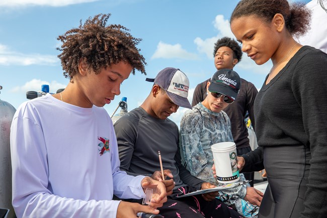 Students looking down and writing down on one paper