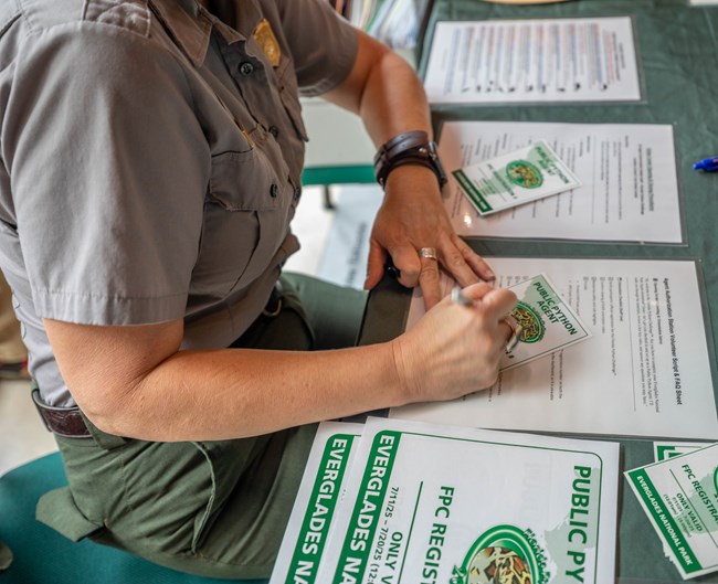 A park ranger sits at a table filling out paperwork for participants