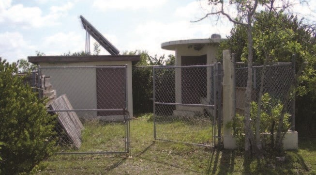 Two small buildings behind a chain link fence