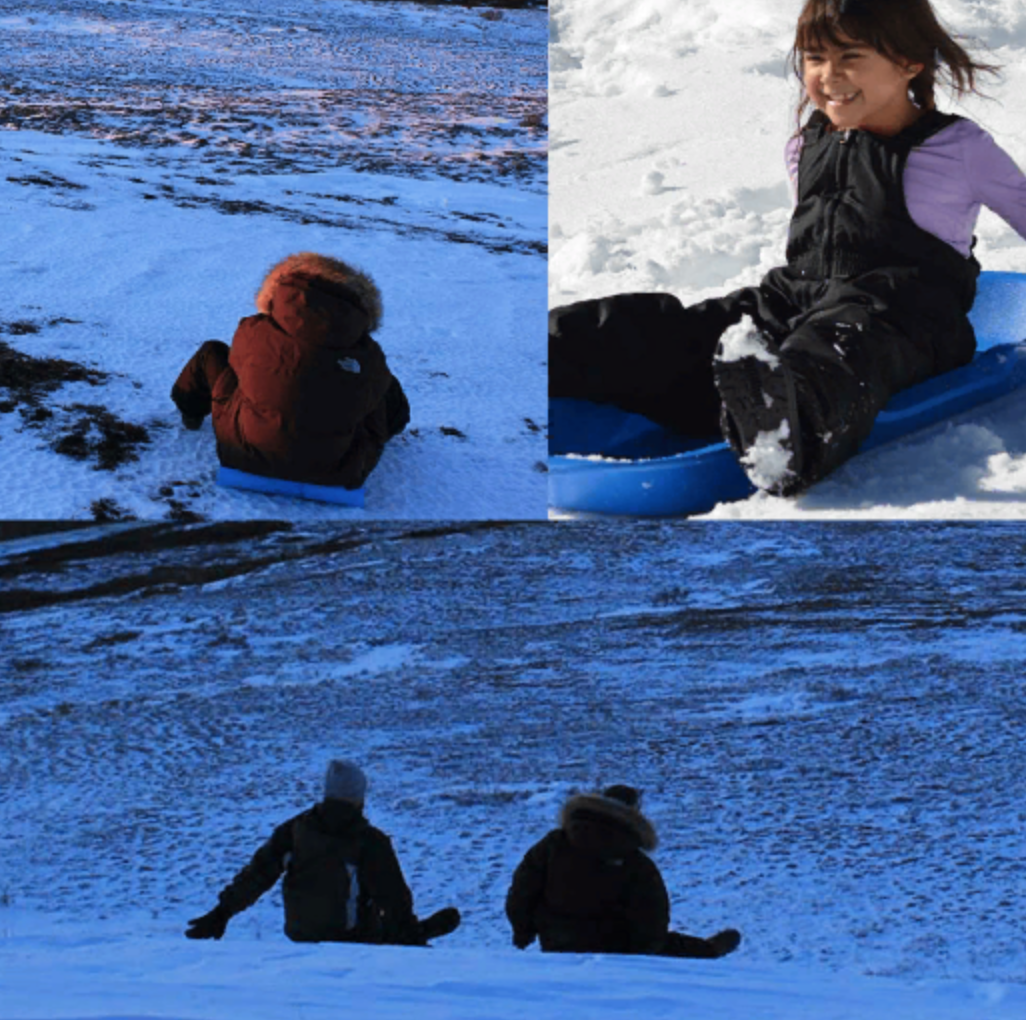 From behind, a woman launches her sled down a hill. 
A young girl sleds down a hill.
From 
behind, two people sled down a hill.