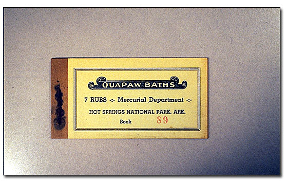 This is a pale yellow colored cover paper with a brown binding covering a staple making the small booklet. The words Quapaw Baths are in a black scroll design. In rows under this are the words: 7 rub-Mercurial Department/Hot Springs National Park, Ark/Book 89 and 89 is stamped in red. There is a double line border around the booklet.