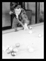 A man playing pool in the recreation building.