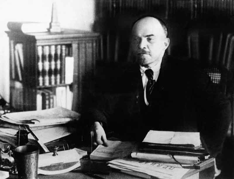 Vladimir Lenin sitting at a desk.