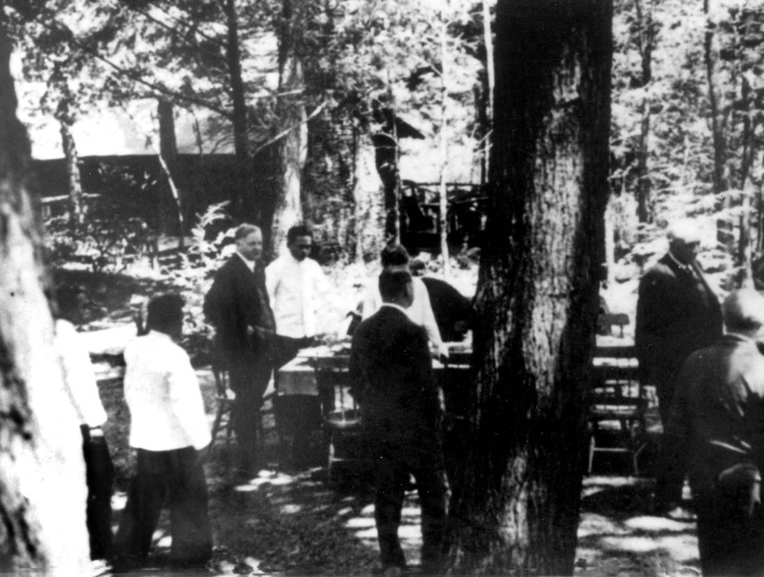 Servants preparing an outdoor table, standing next to President Hoover.