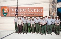 A large group of Park Rangers in uniform stand in front of the Florissant Fossil Beds National Monument visitor center.