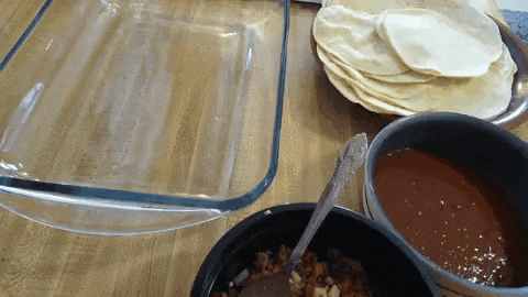 Each tortilla is dipped in red sauce, filled with the meat then rolled and placed in a glass dish. The enchiladas are covered with extra red sauce.