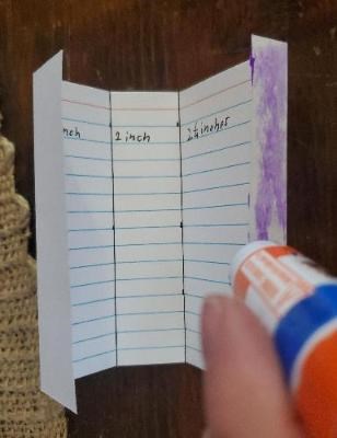 Glue is added to the back of the smallest measured section on the right end of an index card.