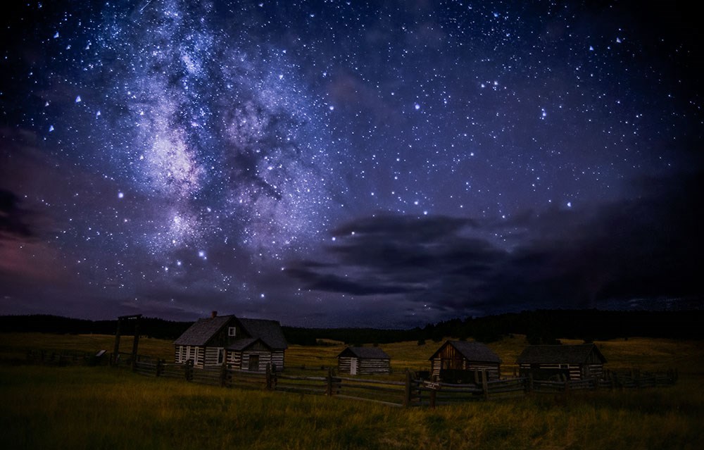 A dark starry night over a historic homestead