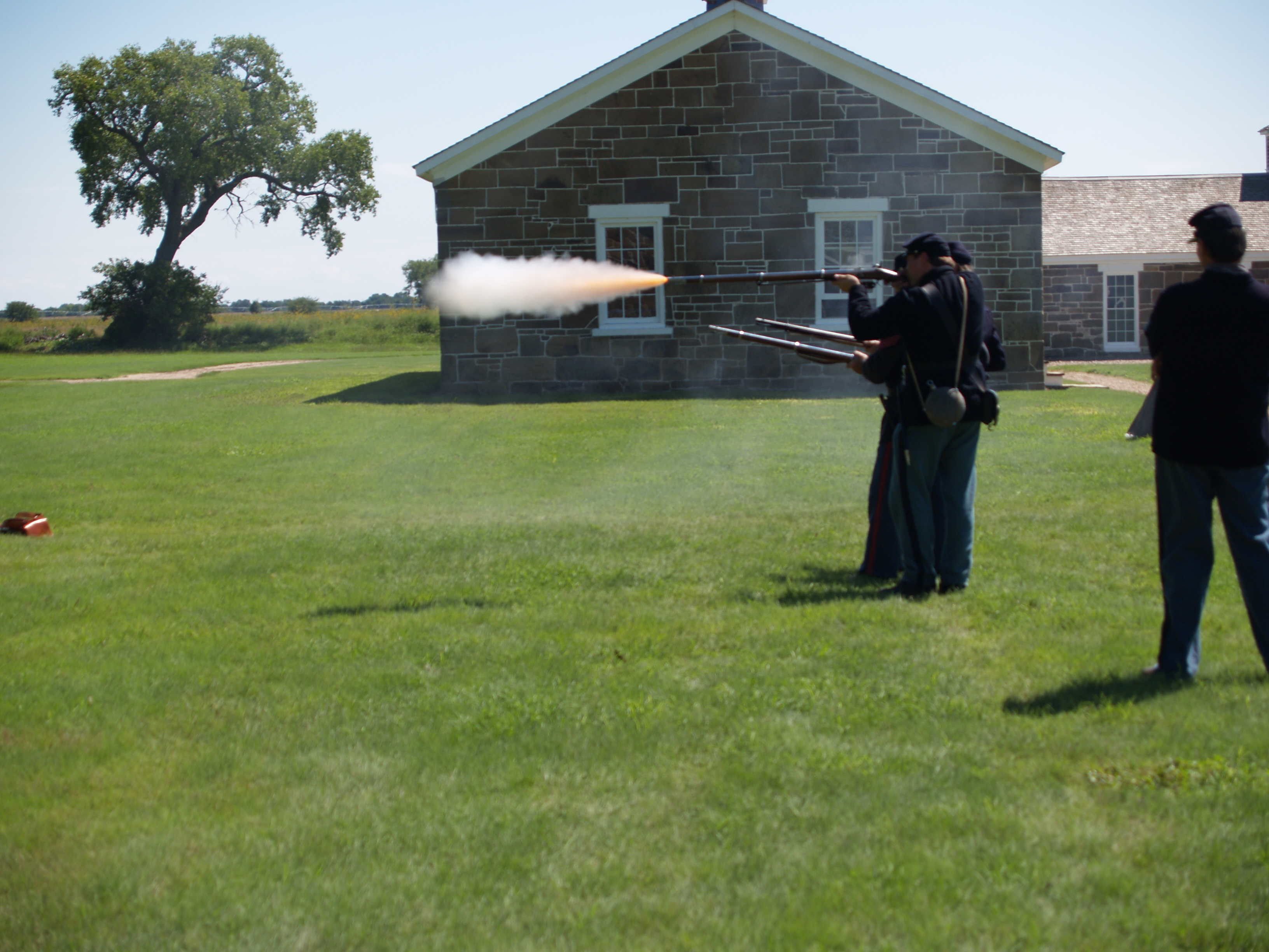 Re-enactors standing in a line firing historic weapons.