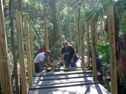 Workers are fastening TREX decking to new frame work for the nature board walk.