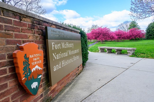 Fort McHenry Welcome sign next to blossoming trees