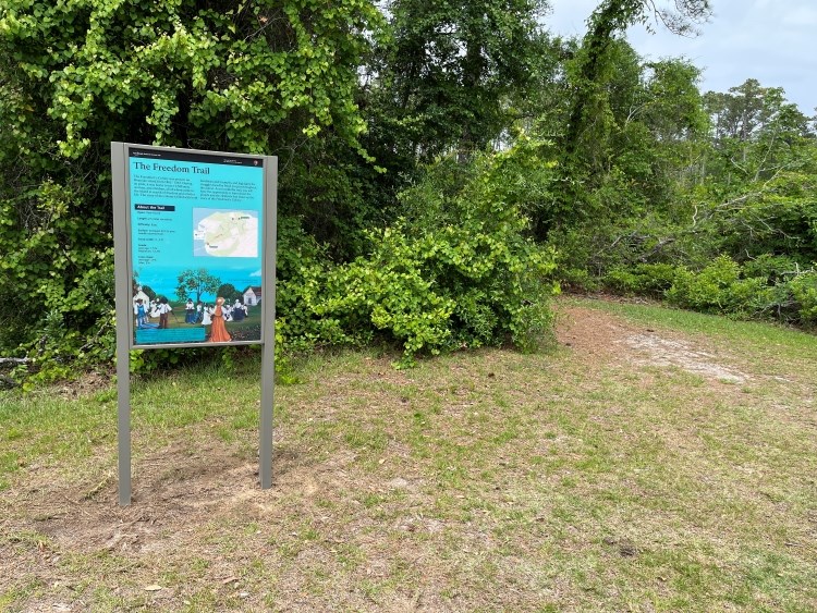 Photo of orientation sign at the entrance to a wooded trail.