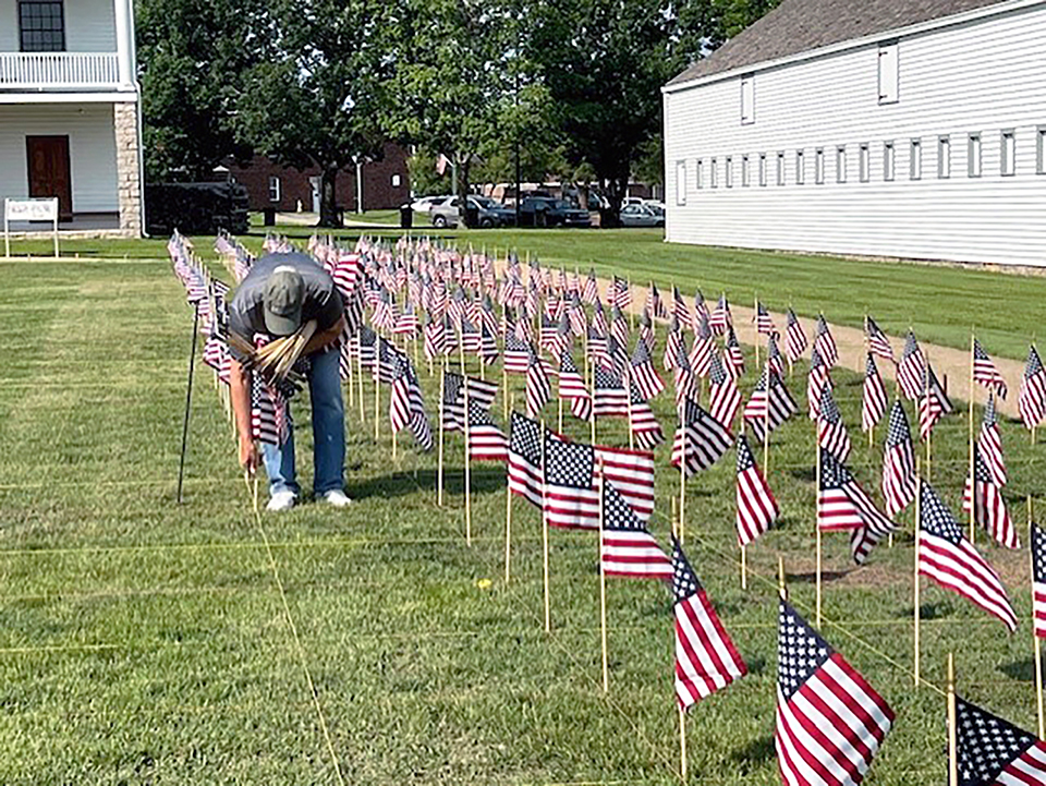 Volunteer helping place small American flags in rows to create a Field of Honor.