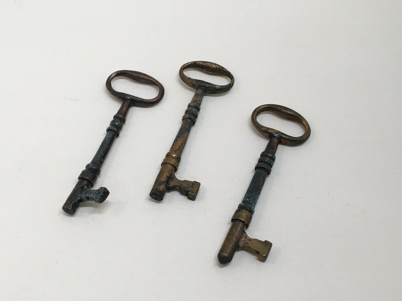 Three skeleton keys about 6 inches long. They are tarnished and pitted, but otherwise in good condition.