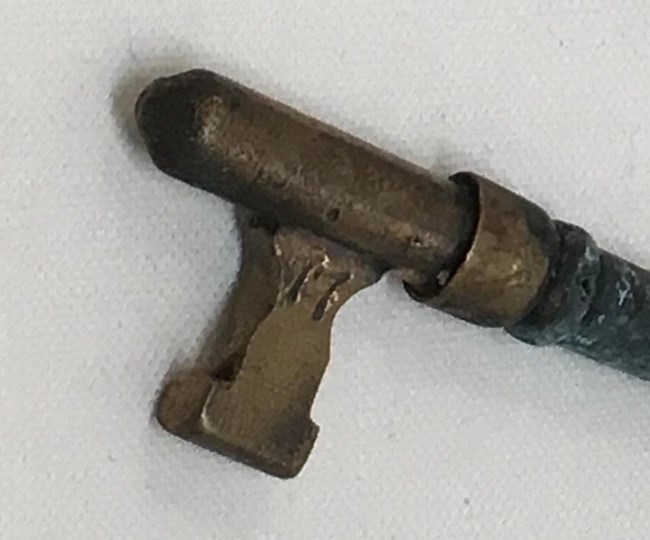 A close up of a brass skeleton key. Zoomed in on the part that enter the keyhole is the number "17" stamped into it.