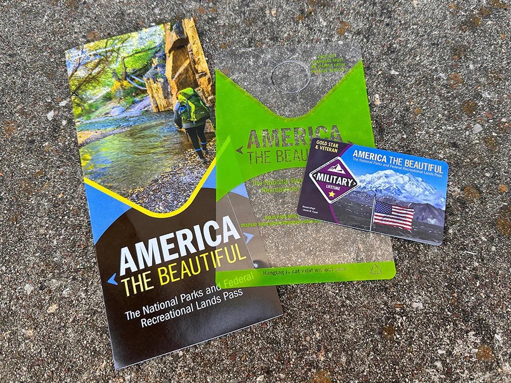 A set of national parks passes, brochures, and pass hangtags arranged in a fan shape.