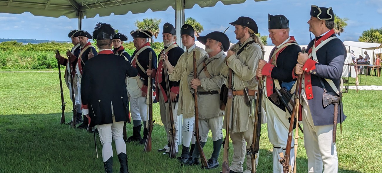 a group of Revolutionary War living historians stand in a line during a program