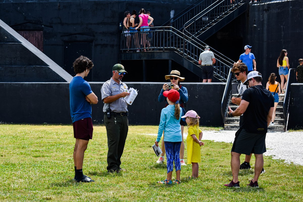 Park Ranger talks to a family in front of a black battery