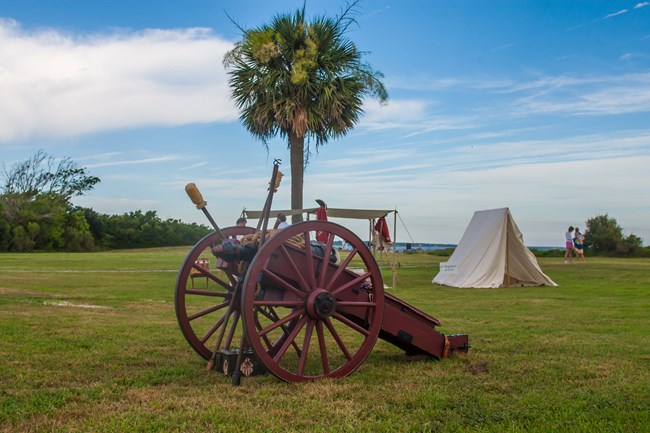 A revolutionary war car sits on a grassy area with a blue sky in the background