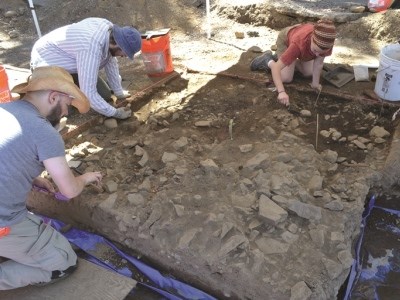 Photo of three students excavating an archaeological unit