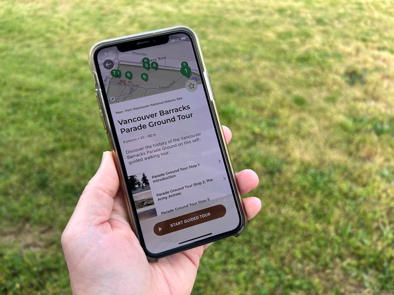 A photo of an iPhone in a person's hand with the Parade Ground self-guided tour open in the NPS App.