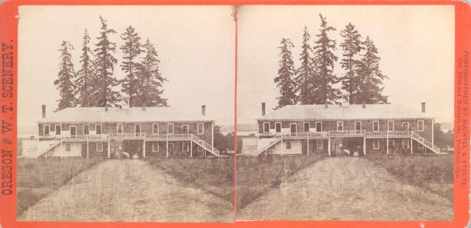 688px-full-guardhouse-stereoscope.jpg A double stereoscope image of a black and white photo of the front of a rectangular two-story building. One end of the lower floor of the building has white brick walls and barred windows.