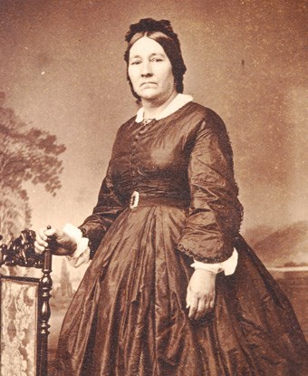 A black and white photo of a woman wearing a dress in a photo studio.