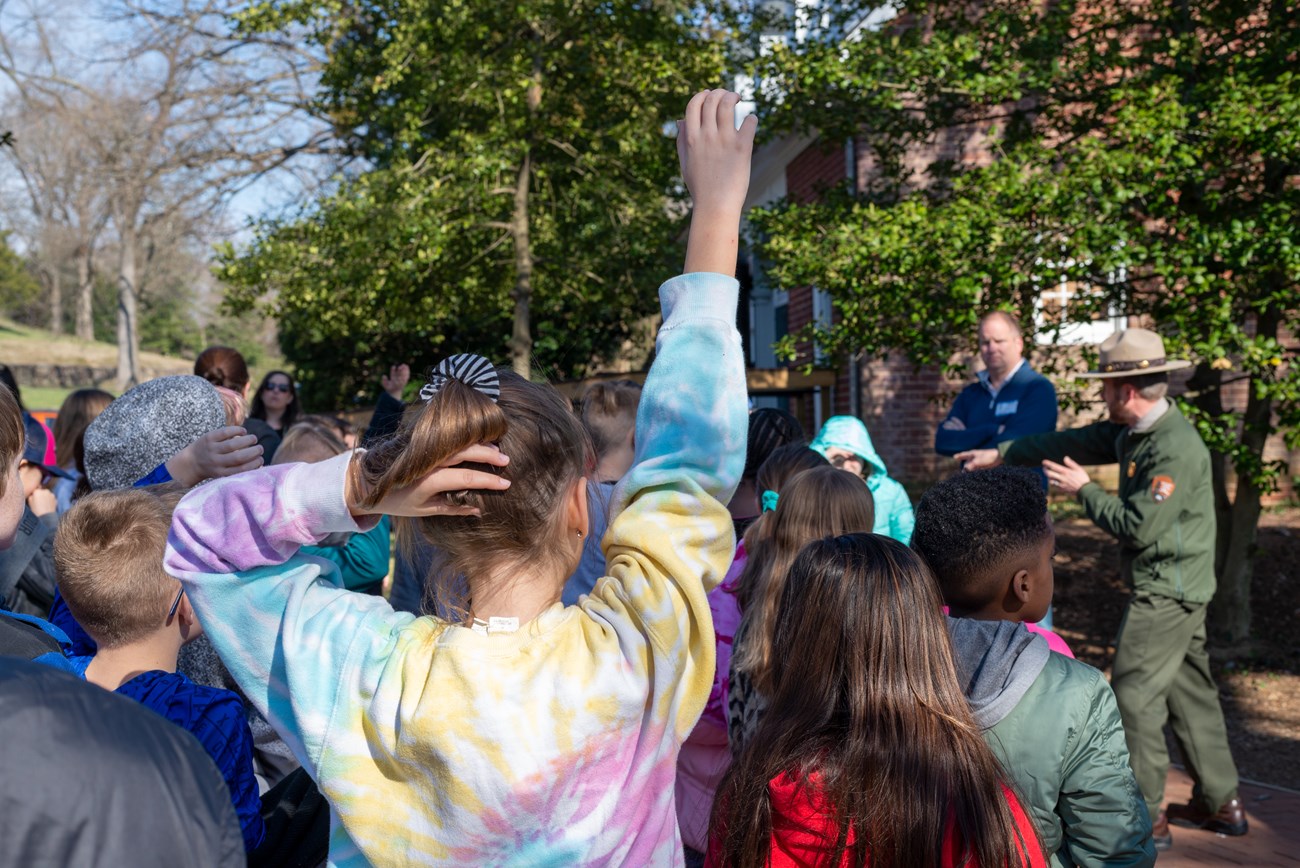 A student raises his hand as a ranger talks to his class.