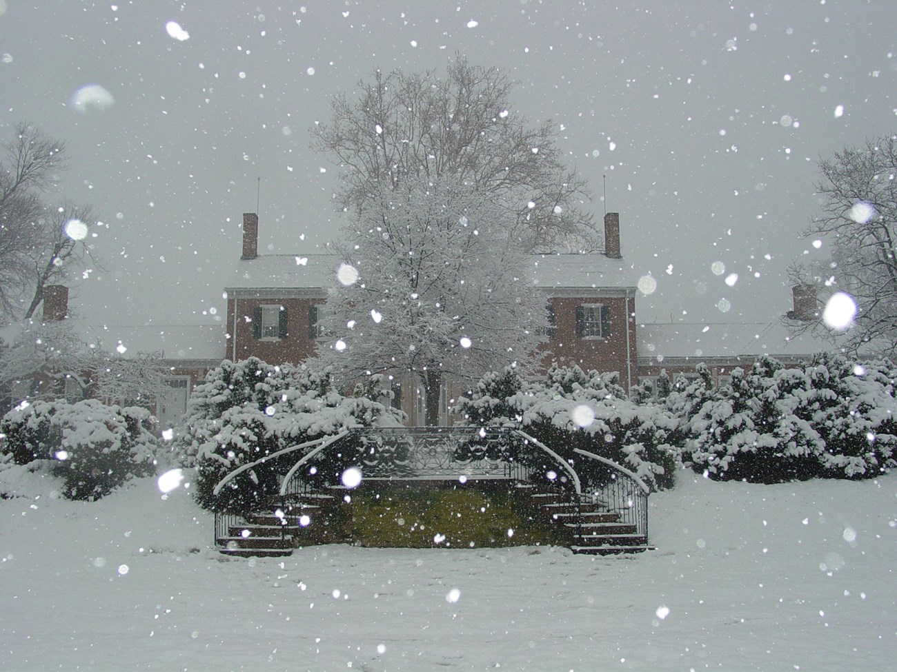 Large brick house with steps leading up to terraces during snow storm