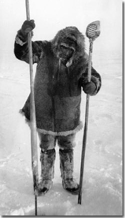 Nunamiut ice fisherman wearing caribou skin parka, pants, and boots