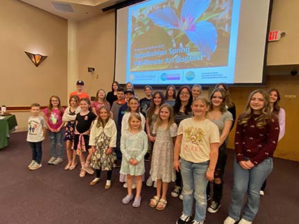 a group of kids pose in front of screen with wildflower