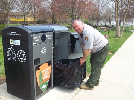 Big modern matte trash bin with an oval inlet, solar panal deployed on top,  black color, deployed at park on Craiyon