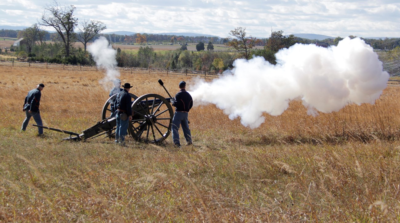 A group of living history performers firing a canon.