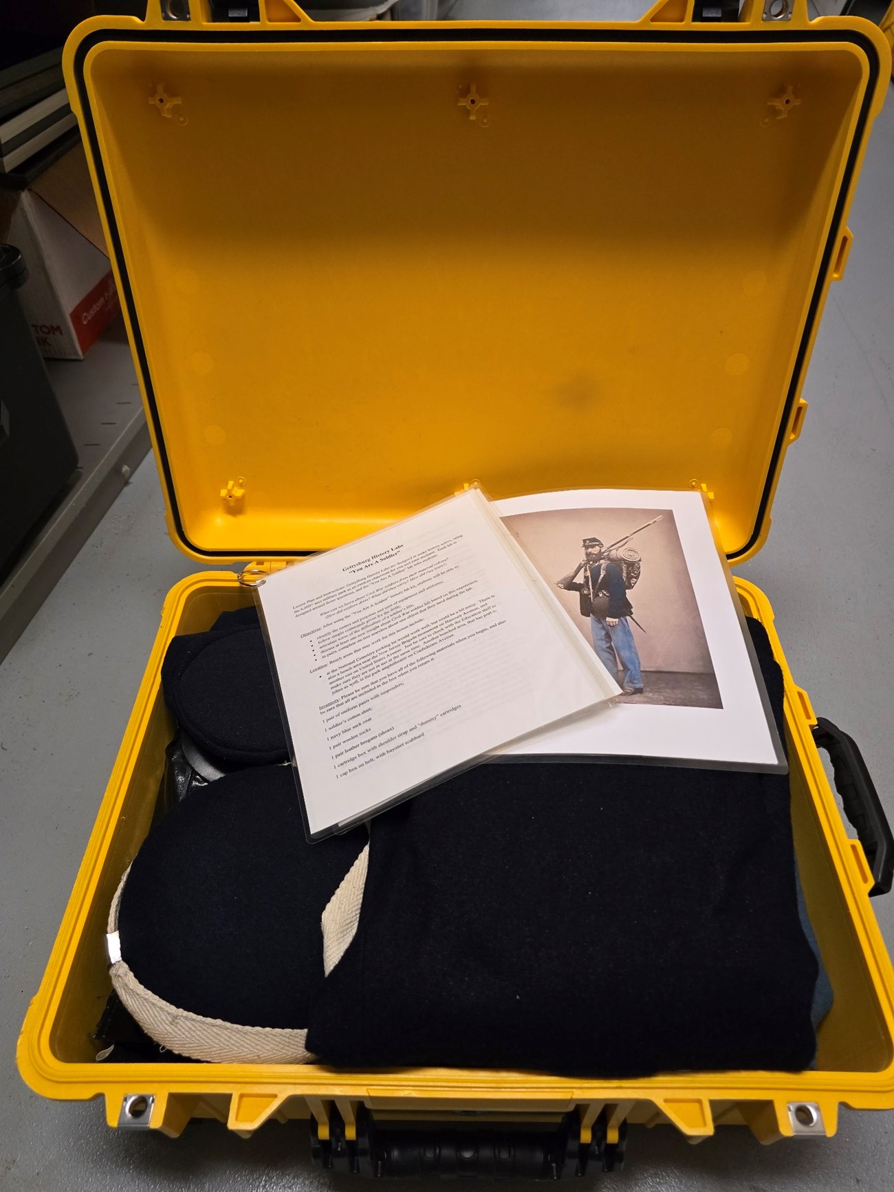 An open yellow trunk contains Civil War soldier uniform items