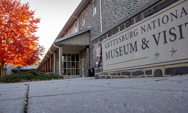 A sign for the Gettysburg Museum and Visitor Center with a vibrant colored tree